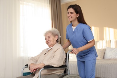 Photo of Healthcare worker with elderly woman in wheelchair indoors