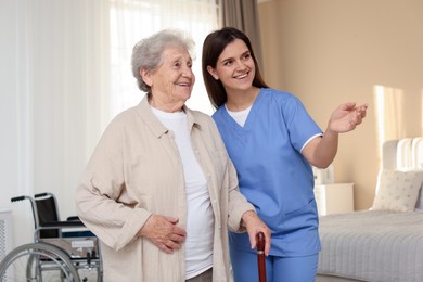 Photo of Smiling healthcare worker and elderly woman looking at something indoors