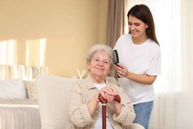 Photo of Granddaughter brushing her grandmother with comb at home. Elderly care