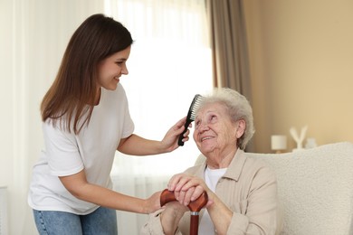 Photo of Granddaughter brushing her grandmother with comb at home. Elderly care