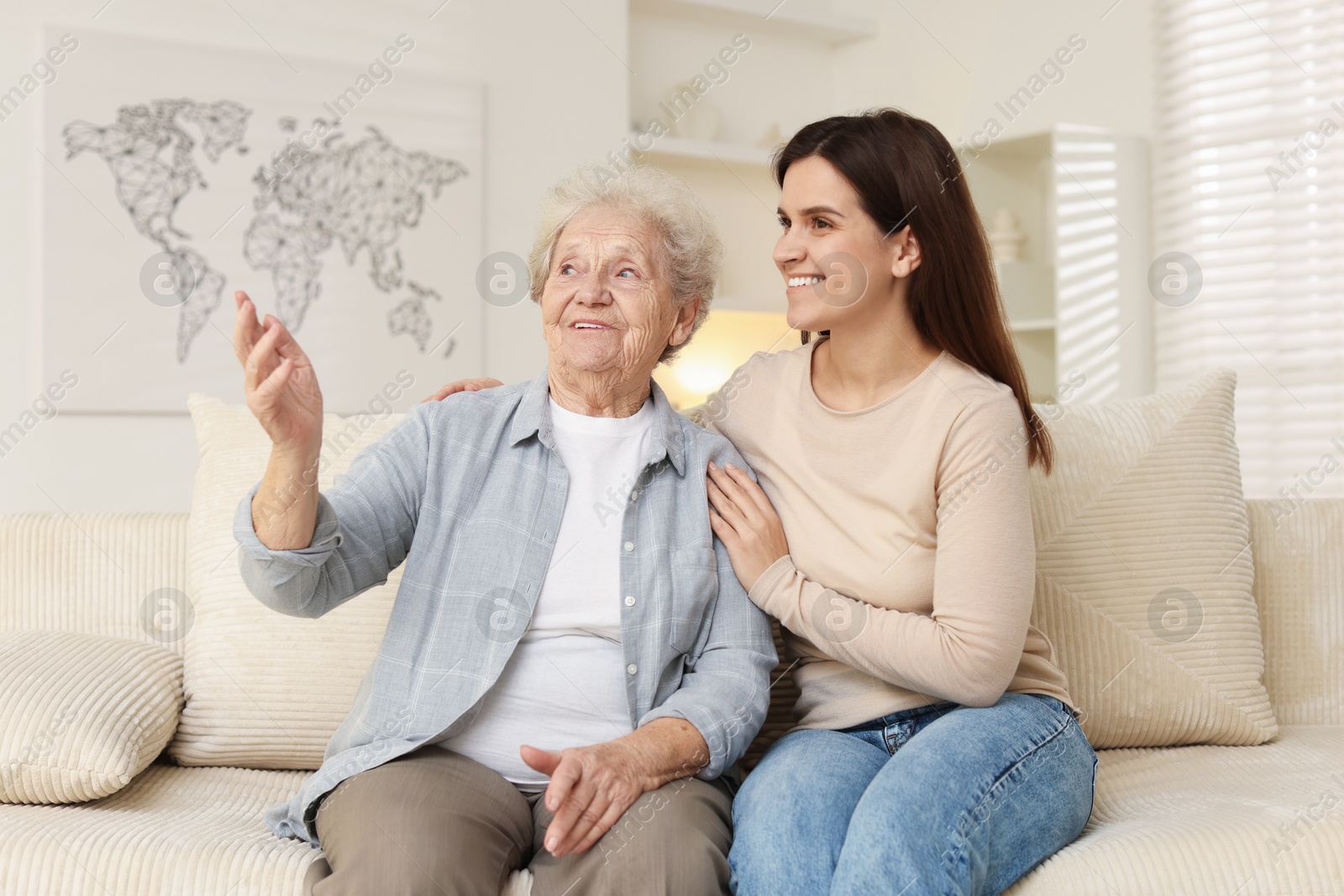 Photo of Granddaughter with her grandmother looking at something indoors. Elderly care