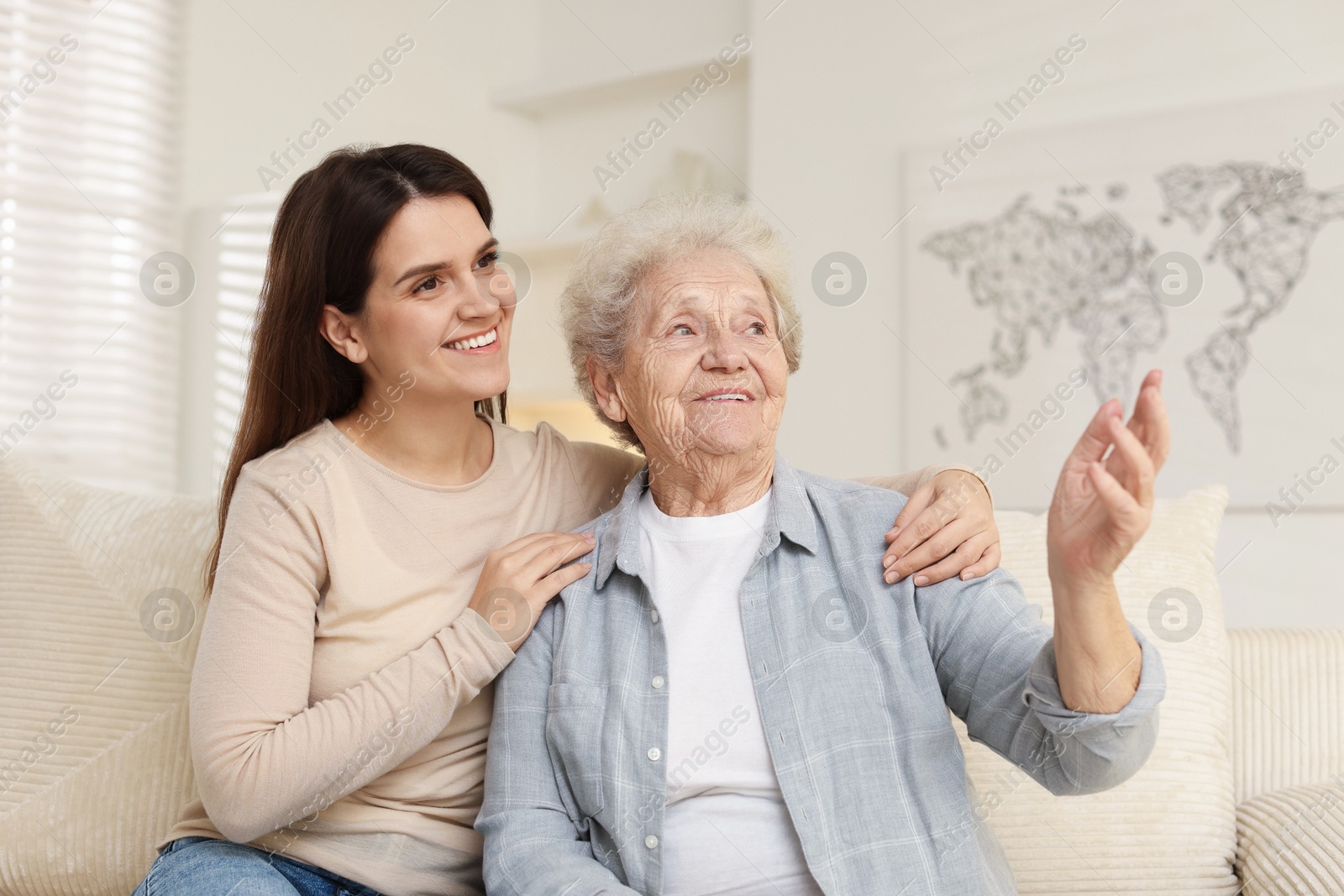 Photo of Granddaughter with her grandmother looking at something indoors. Elderly care