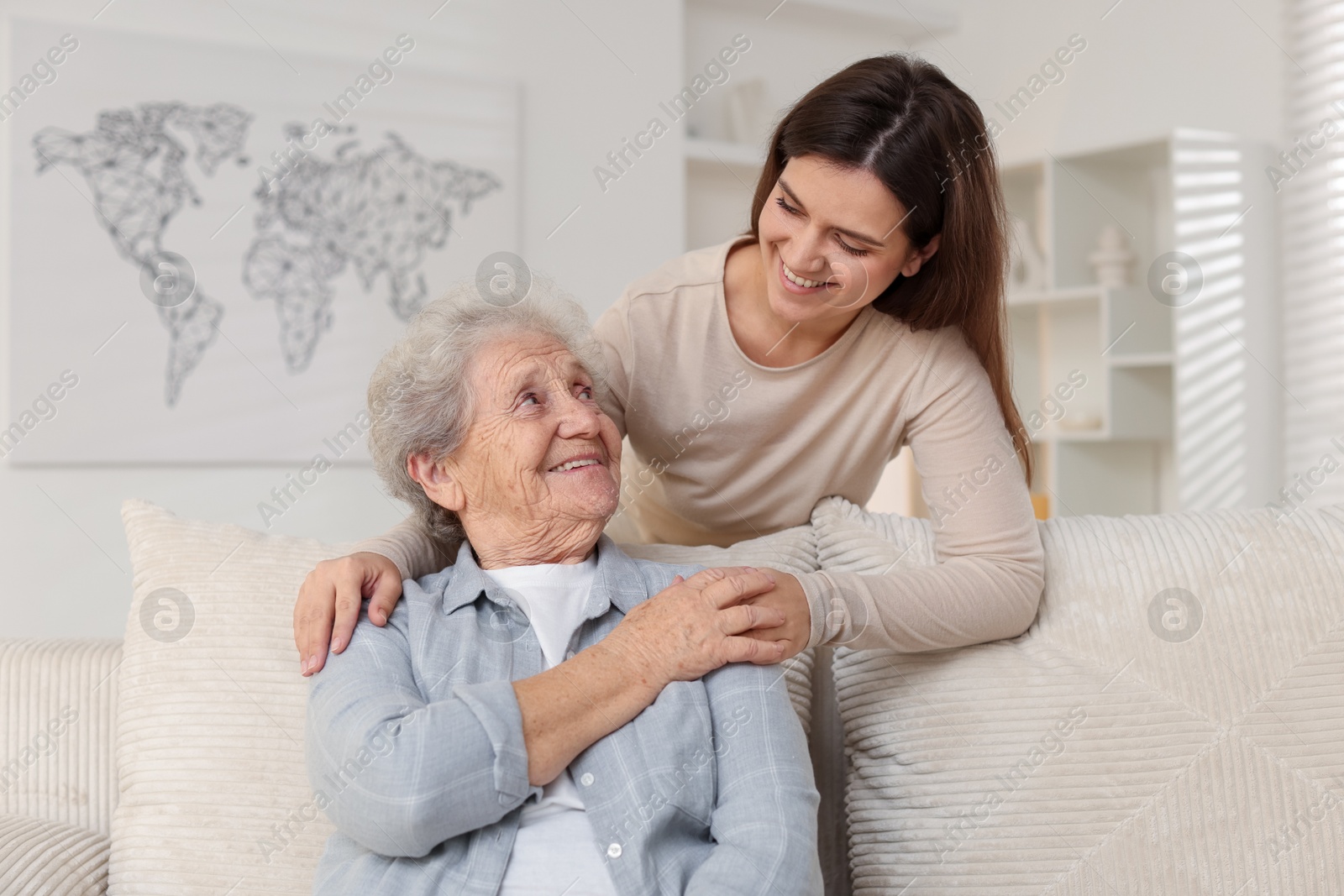 Photo of Happy granddaughter with her grandmother on sofa at home. Elderly care