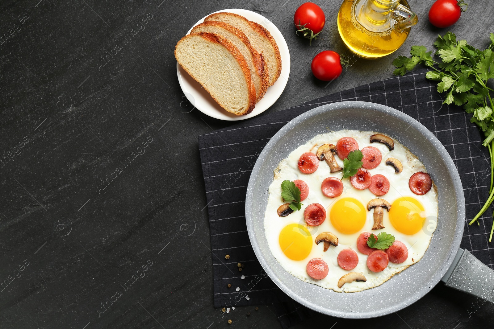 Photo of Tasty fried eggs with cut sausages and mushrooms served on black table, flat lay. Space for text