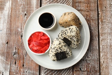 Photo of Rice balls (onigiri), soy sauce and pickled ginger on wooden table, top view. Traditional Japanese dish