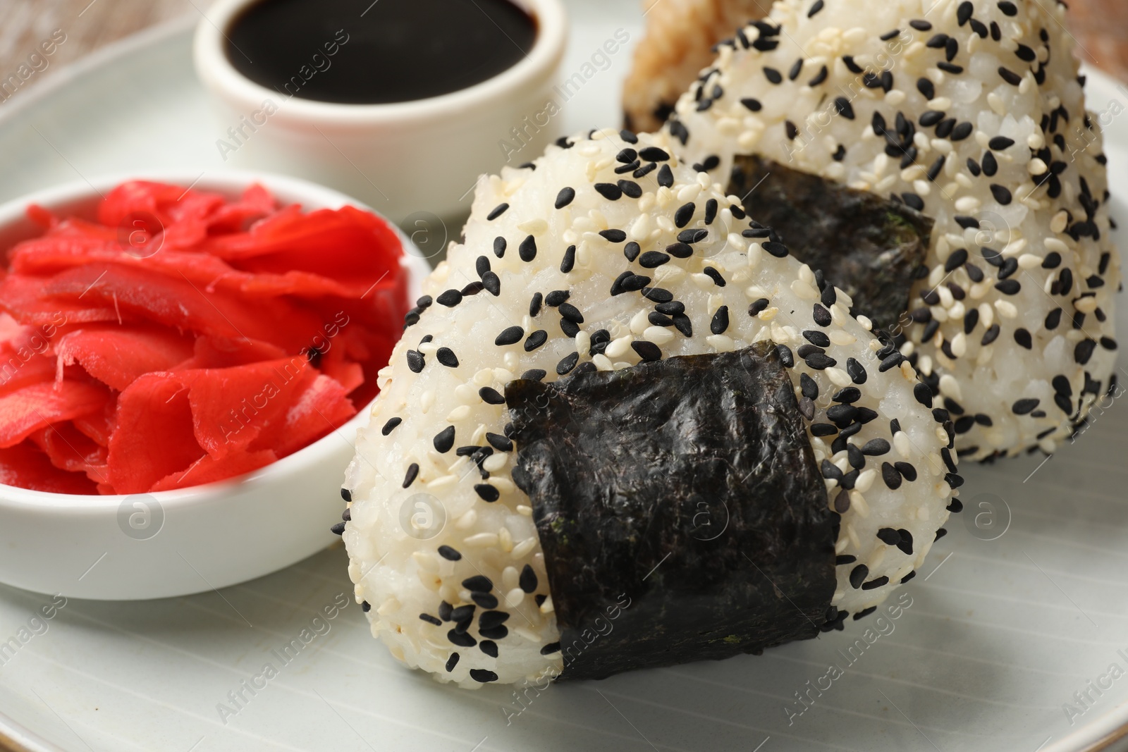 Photo of Rice balls (onigiri), soy sauce and pickled ginger on plate, closeup. Traditional Japanese dish