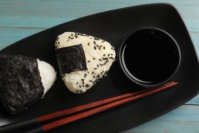 Photo of Rice balls (onigiri) served on light blue wooden table, top view. Traditional Japanese dish