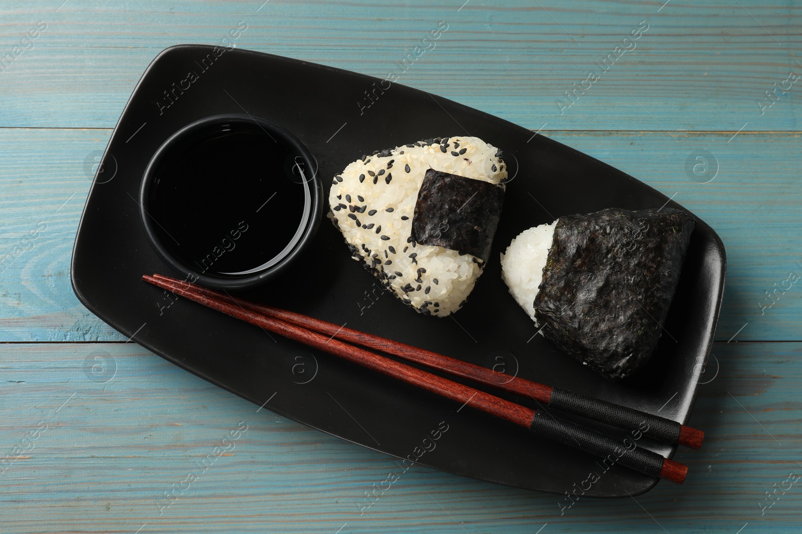 Photo of Rice balls (onigiri) served on light blue wooden table, top view. Traditional Japanese dish