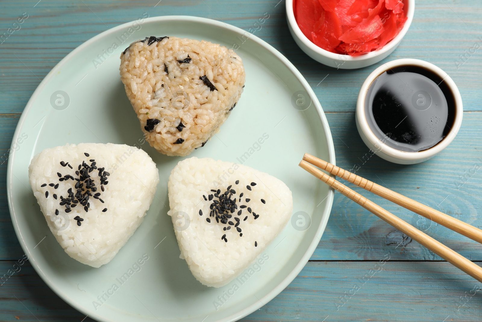 Photo of Rice balls (onigiri) served on light blue wooden table, flat lay. Traditional Japanese dish