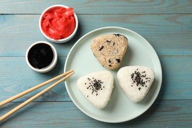 Photo of Rice balls (onigiri) served on light blue wooden table, flat lay. Traditional Japanese dish