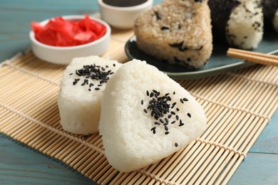 Photo of Rice balls (onigiri) served on light blue wooden table, closeup. Traditional Japanese dish