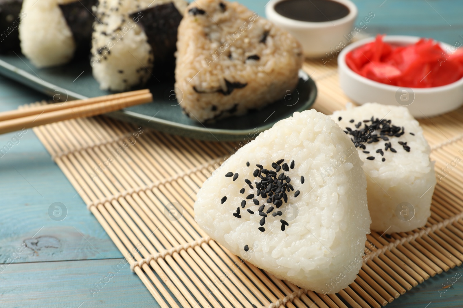 Photo of Rice balls (onigiri) served on light blue wooden table, closeup. Traditional Japanese dish