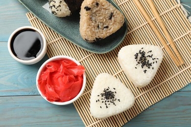 Photo of Rice balls (onigiri) served on light blue wooden table, flat lay. Traditional Japanese dish