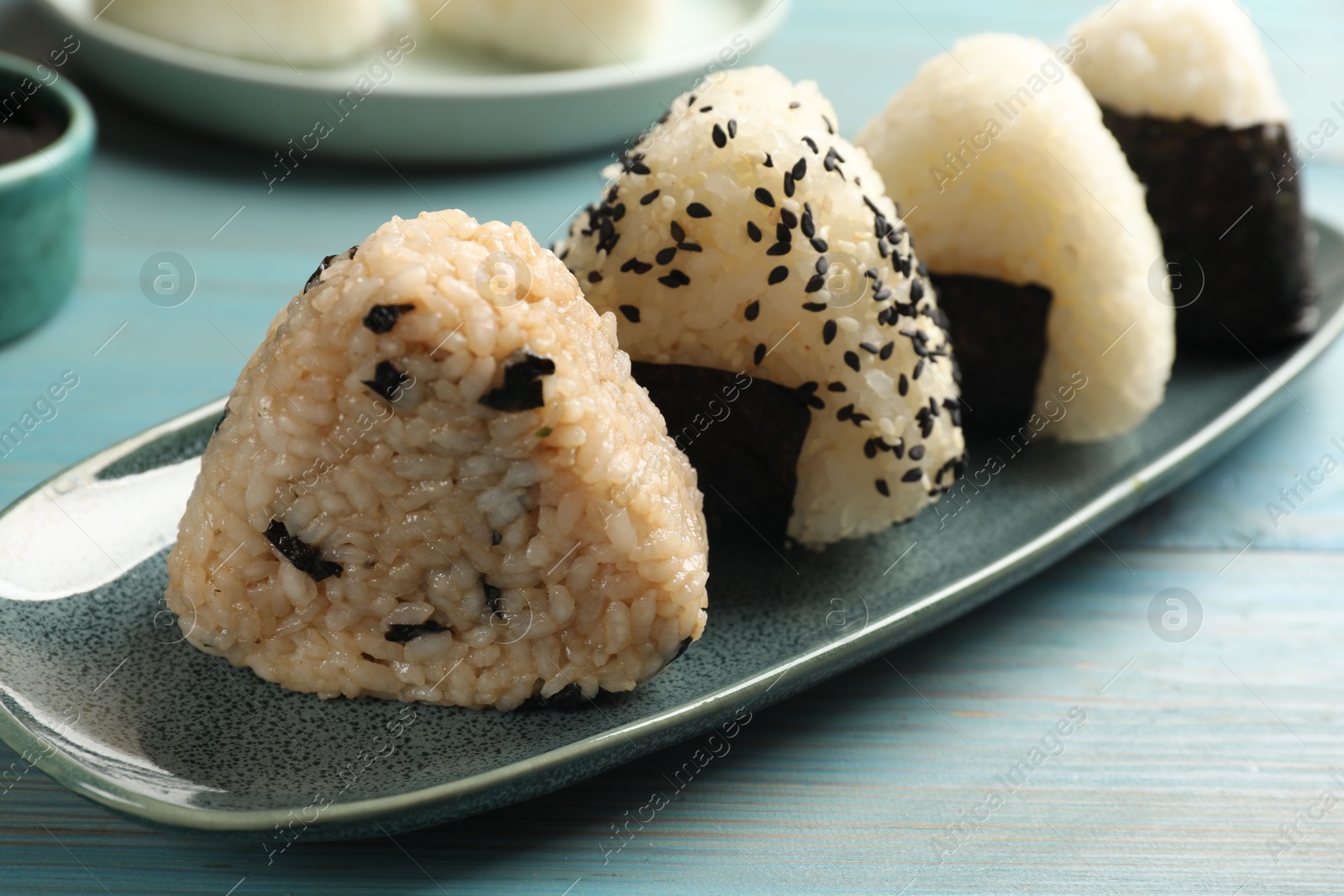 Photo of Rice balls (onigiri) on light blue wooden table, closeup. Traditional Japanese dish