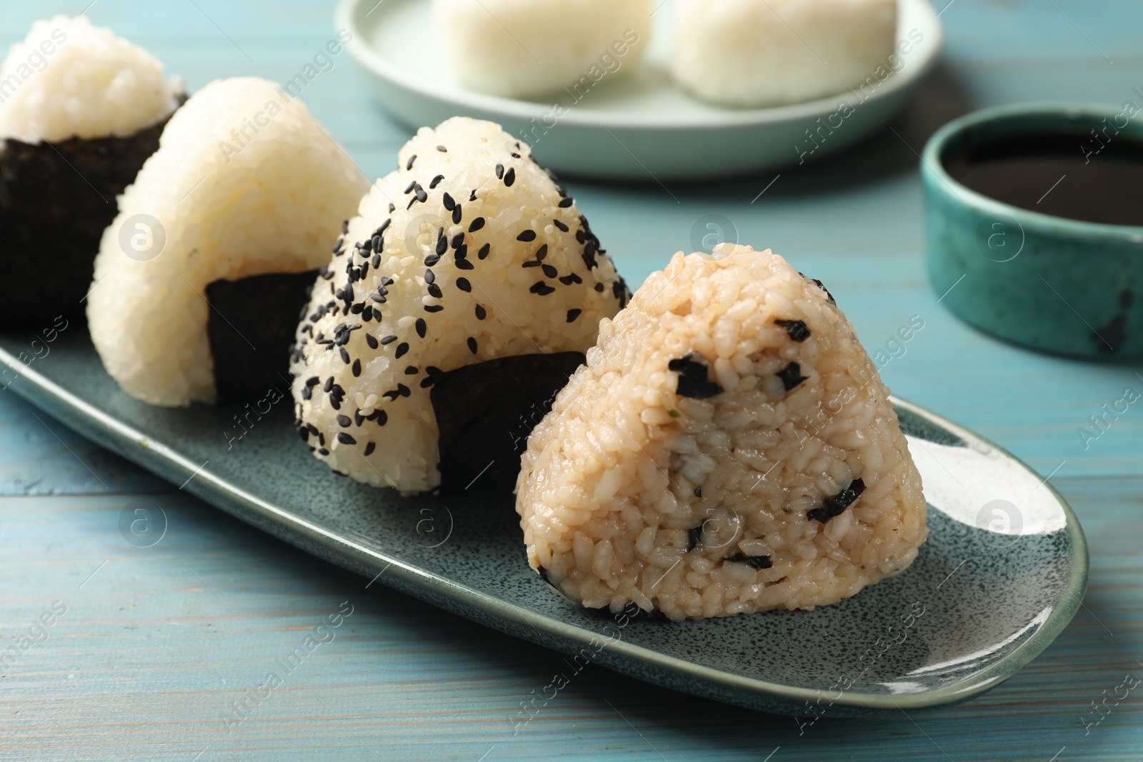 Photo of Rice balls (onigiri) on light blue wooden table, closeup. Traditional Japanese dish