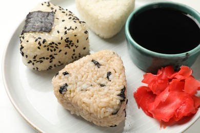 Photo of Rice balls (onigiri), soy sauce and pickled ginger on table, closeup. Traditional Japanese dish