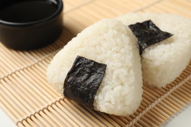 Photo of Rice balls (onigiri) and soy sauce on table, closeup. Traditional Japanese dish