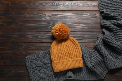 Photo of Knitted scarf and hat on wooden table, top view. Space for text