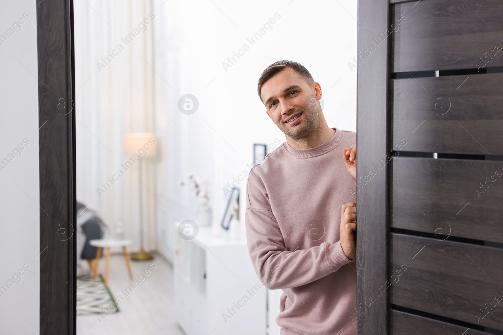 Photo of Cheerful man welcoming guests to his apartment. Space for text