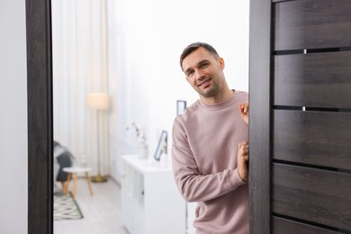 Photo of Cheerful man welcoming guests to his apartment. Space for text