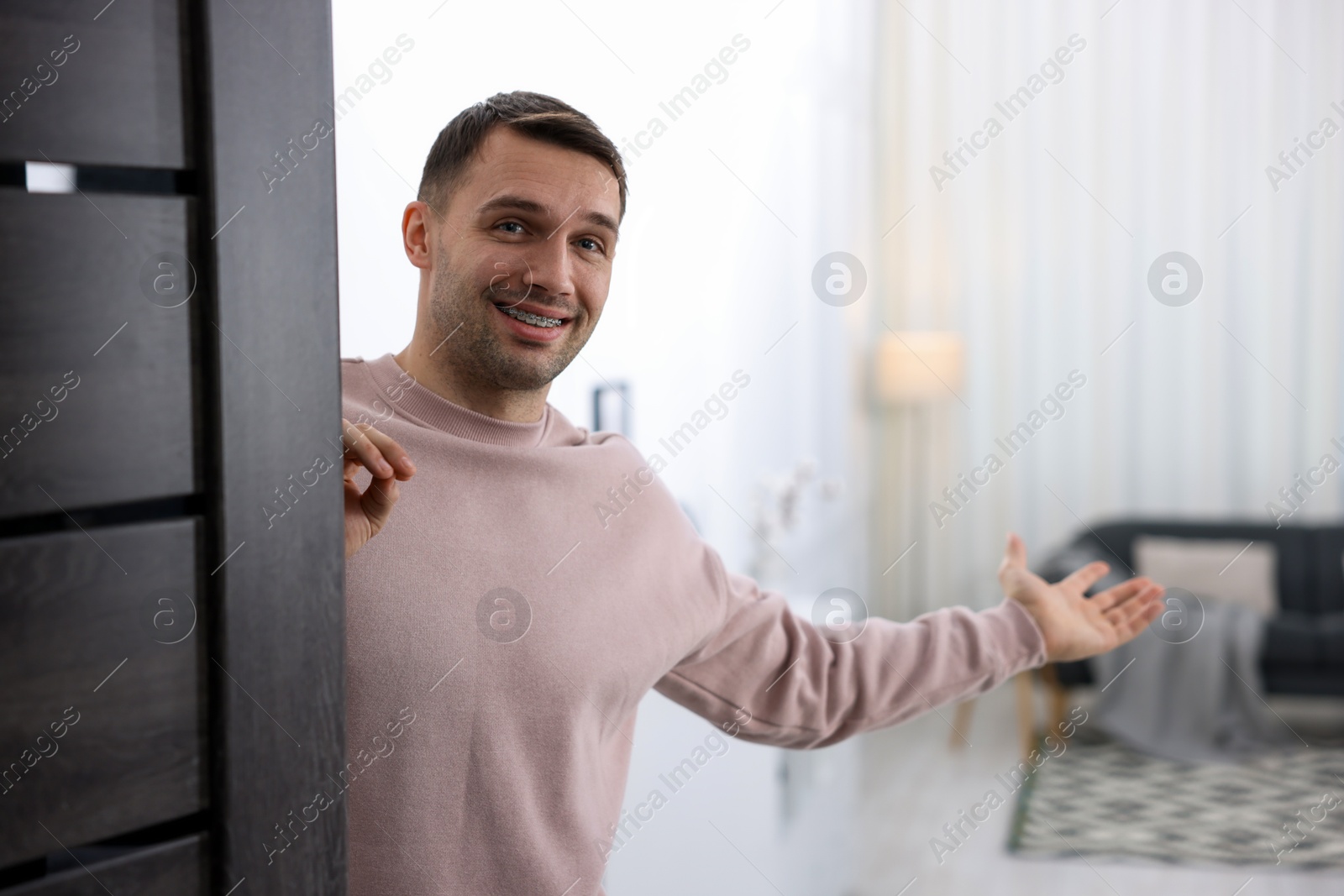 Photo of Cheerful man welcoming guests to his apartment