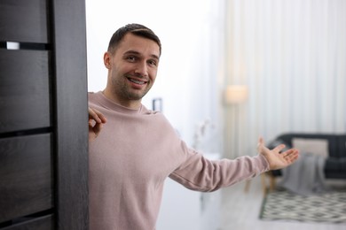 Cheerful man welcoming guests to his apartment