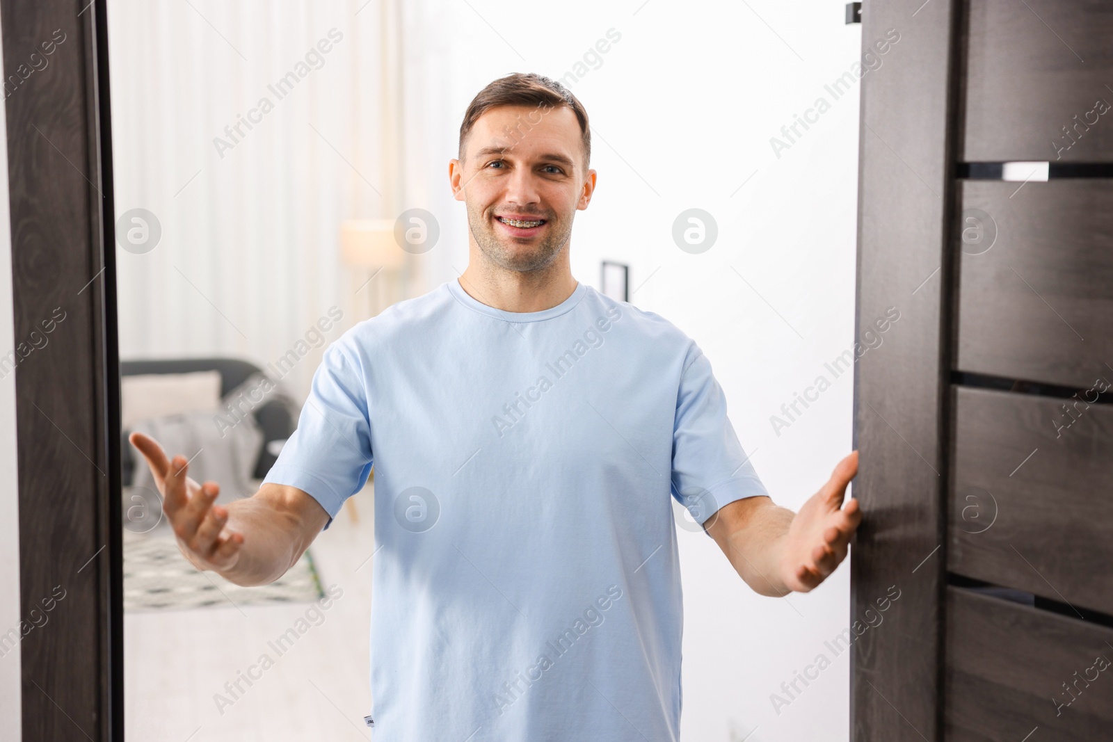 Photo of Cheerful man welcoming guests to his apartment