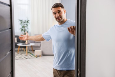 Photo of Cheerful man welcoming guests to his apartment