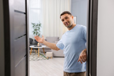 Photo of Cheerful man welcoming guests to his apartment