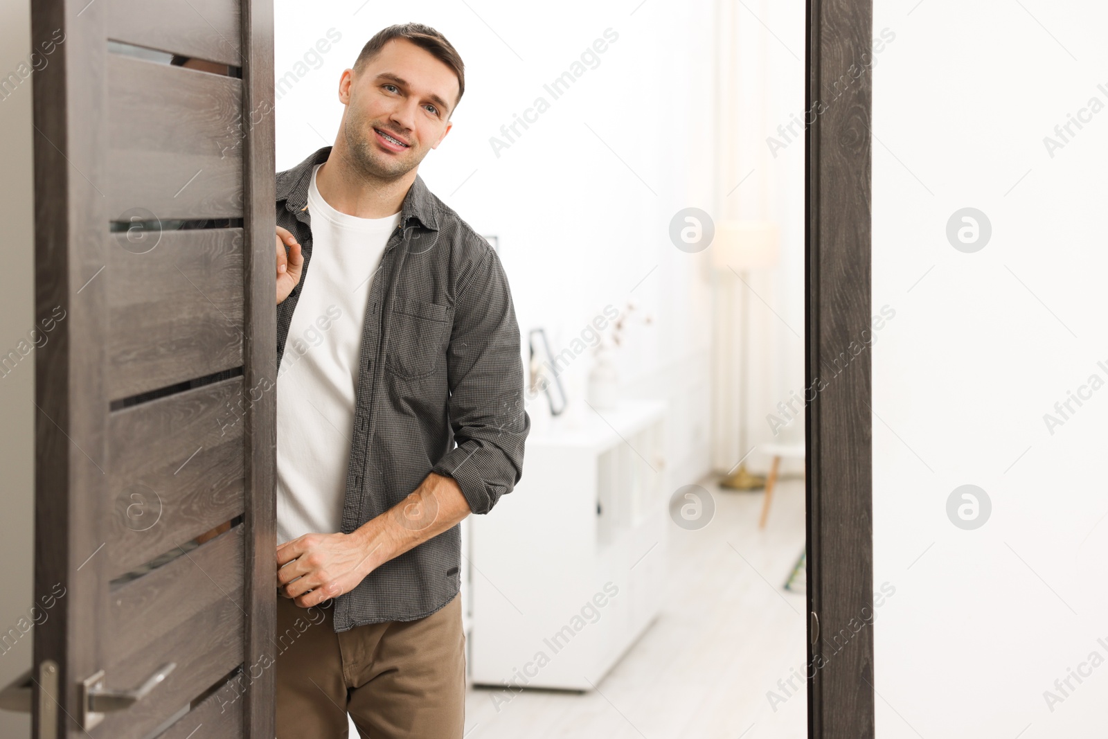 Photo of Cheerful man welcoming guests to his apartment. Space for text