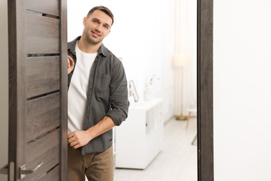 Photo of Cheerful man welcoming guests to his apartment. Space for text