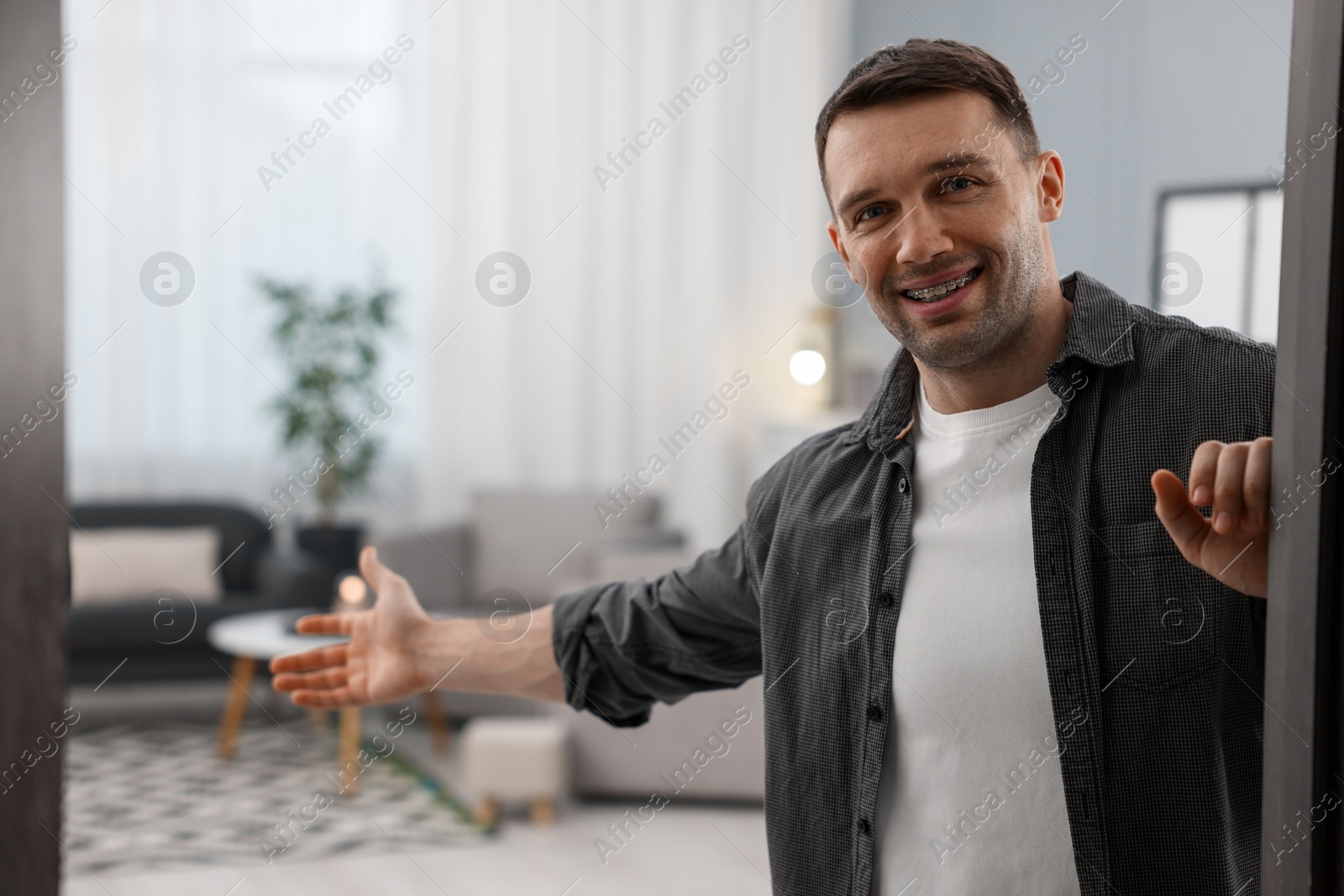 Photo of Cheerful man welcoming guests to his apartment. Space for text