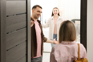 Photo of Lovely couple welcoming friend to their apartment