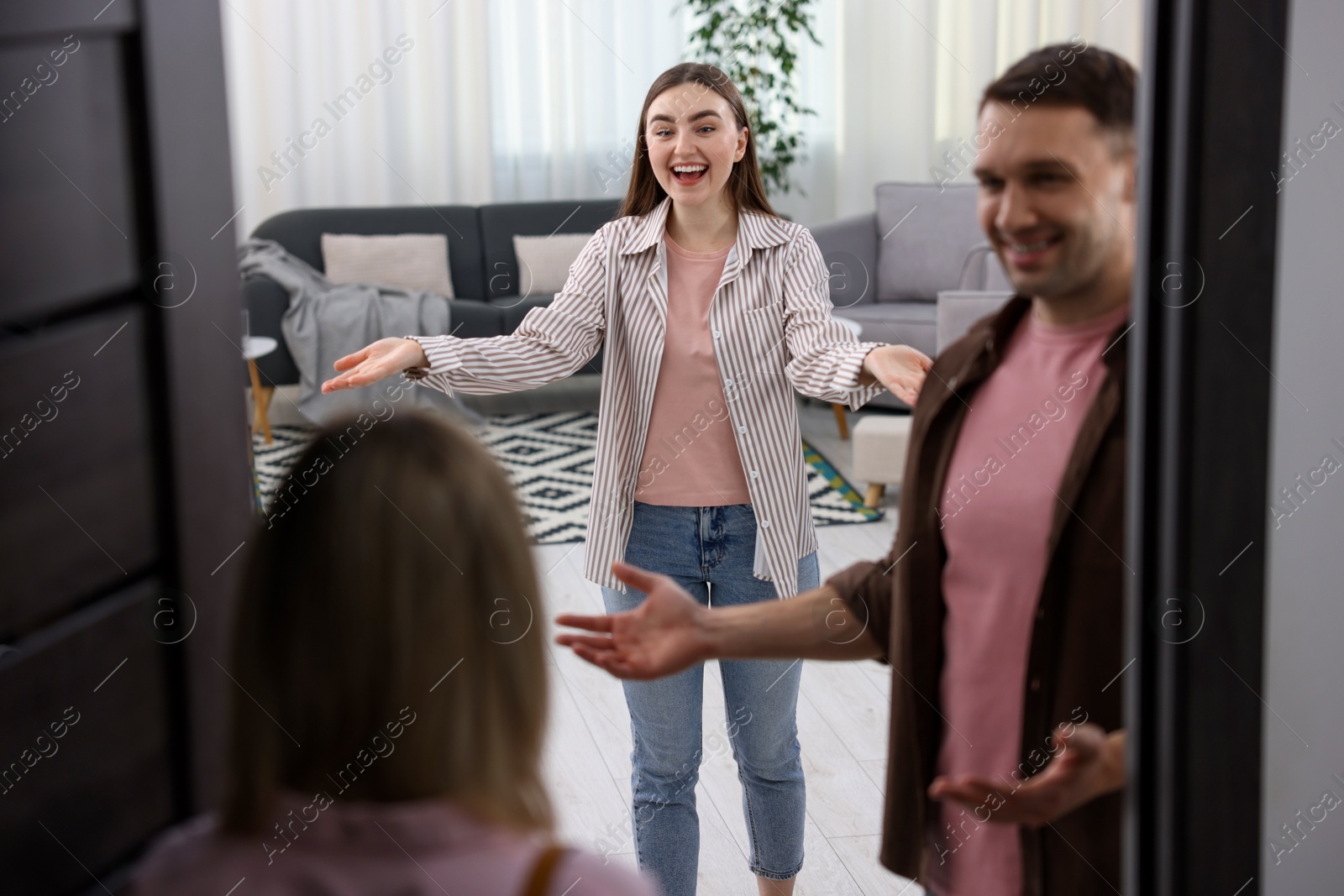 Photo of Lovely couple welcoming friend to their apartment