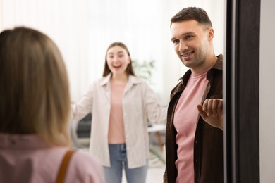 Photo of Lovely couple welcoming friend to their apartment