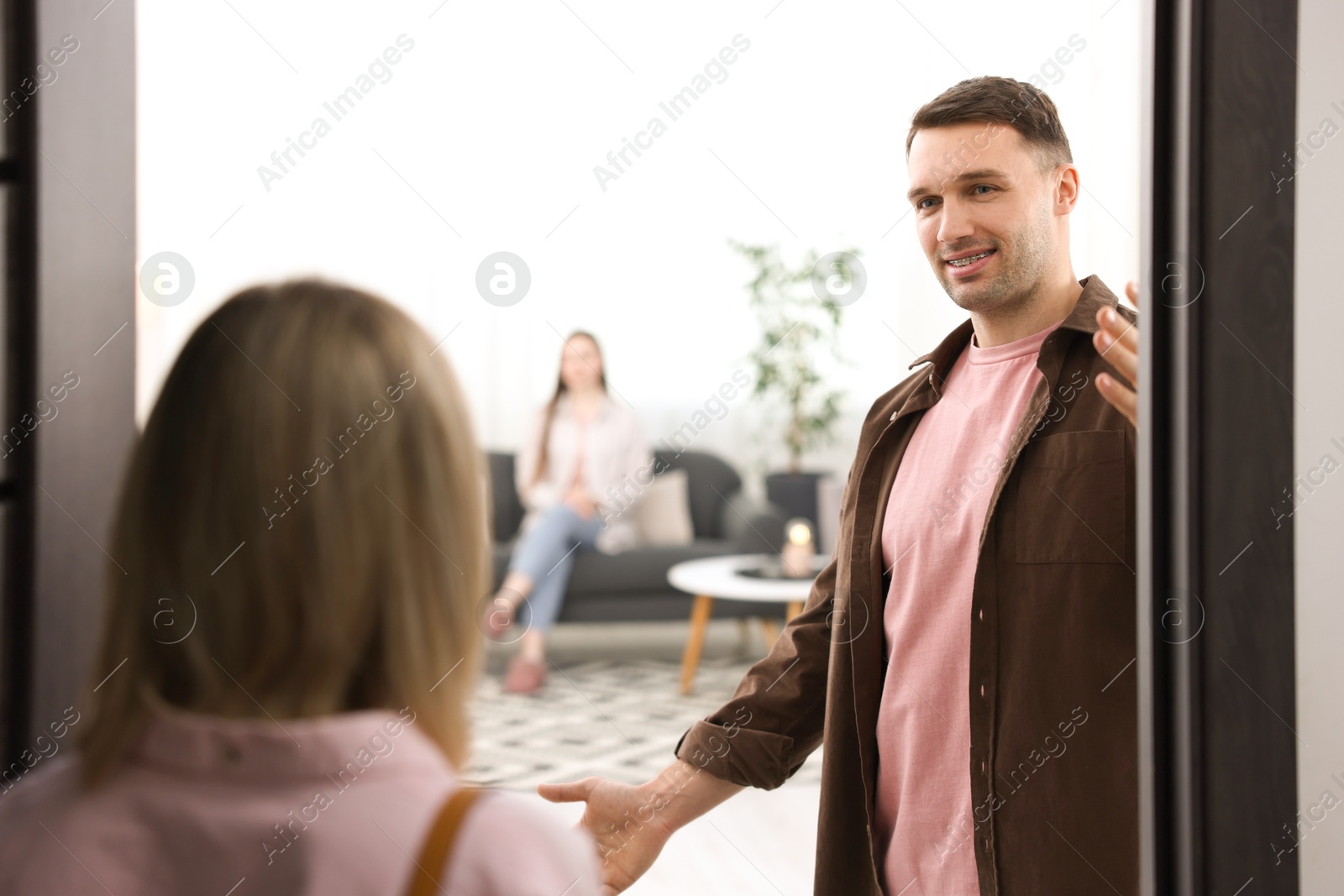 Photo of Lovely couple welcoming friend to their apartment