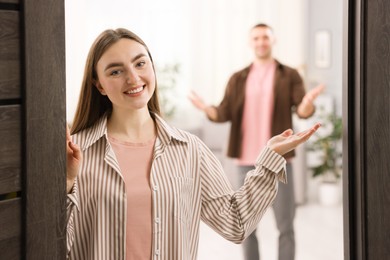 Photo of Lovely couple welcoming guests to their apartment, selective focus