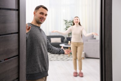 Photo of Happy couple welcoming guests to their apartment, selective focus