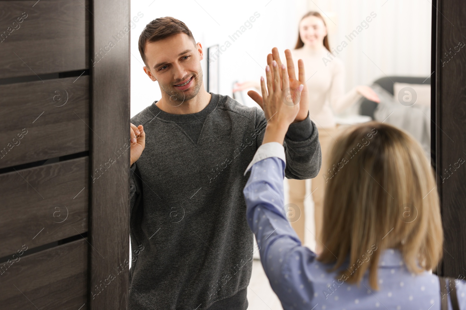 Photo of Lovely couple welcoming friend to their apartment, selective focus