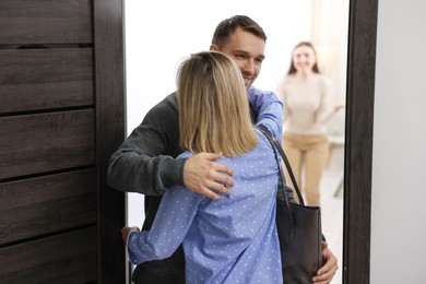 Photo of Lovely couple welcoming friend to their apartment, selective focus