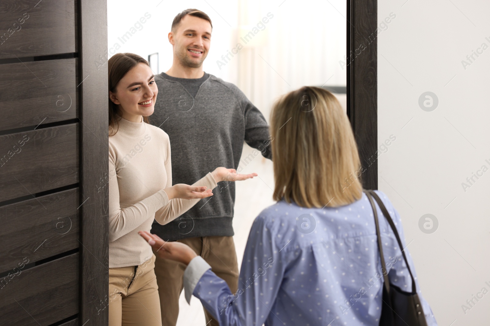 Photo of Lovely couple welcoming friend to their apartment