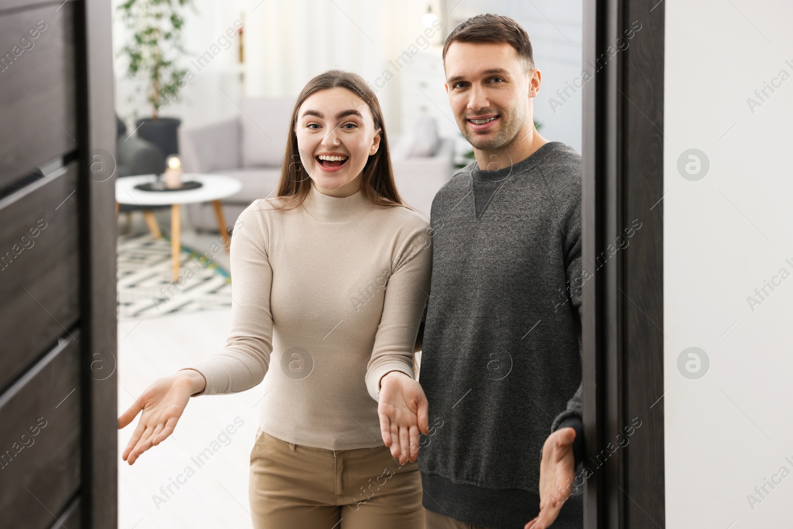 Photo of Excited couple welcoming friends to their apartment