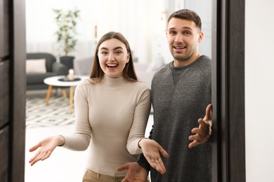 Photo of Excited couple welcoming friends to their apartment