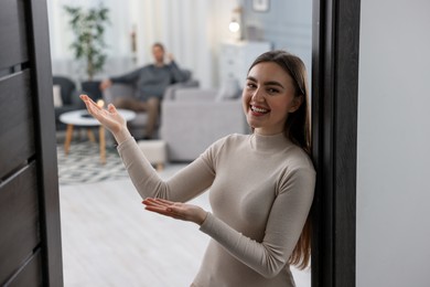 Photo of Happy woman welcoming guests to her apartment