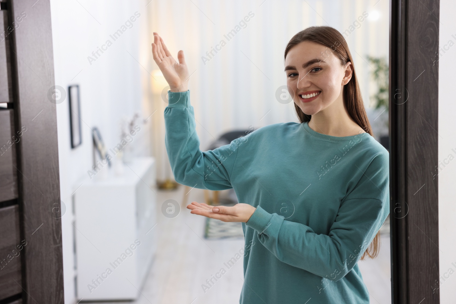 Photo of Cheerful woman welcoming guests to her apartment