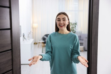 Photo of Cheerful woman welcoming guests to her apartment