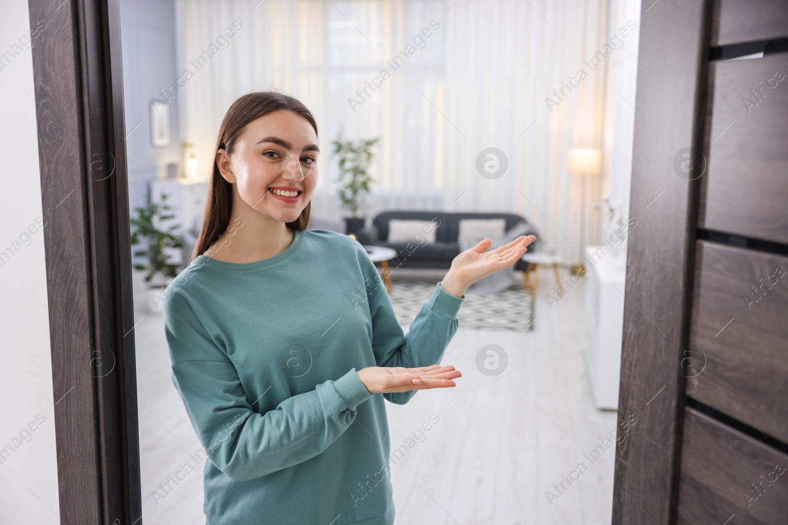 Photo of Cheerful woman welcoming guests to her apartment