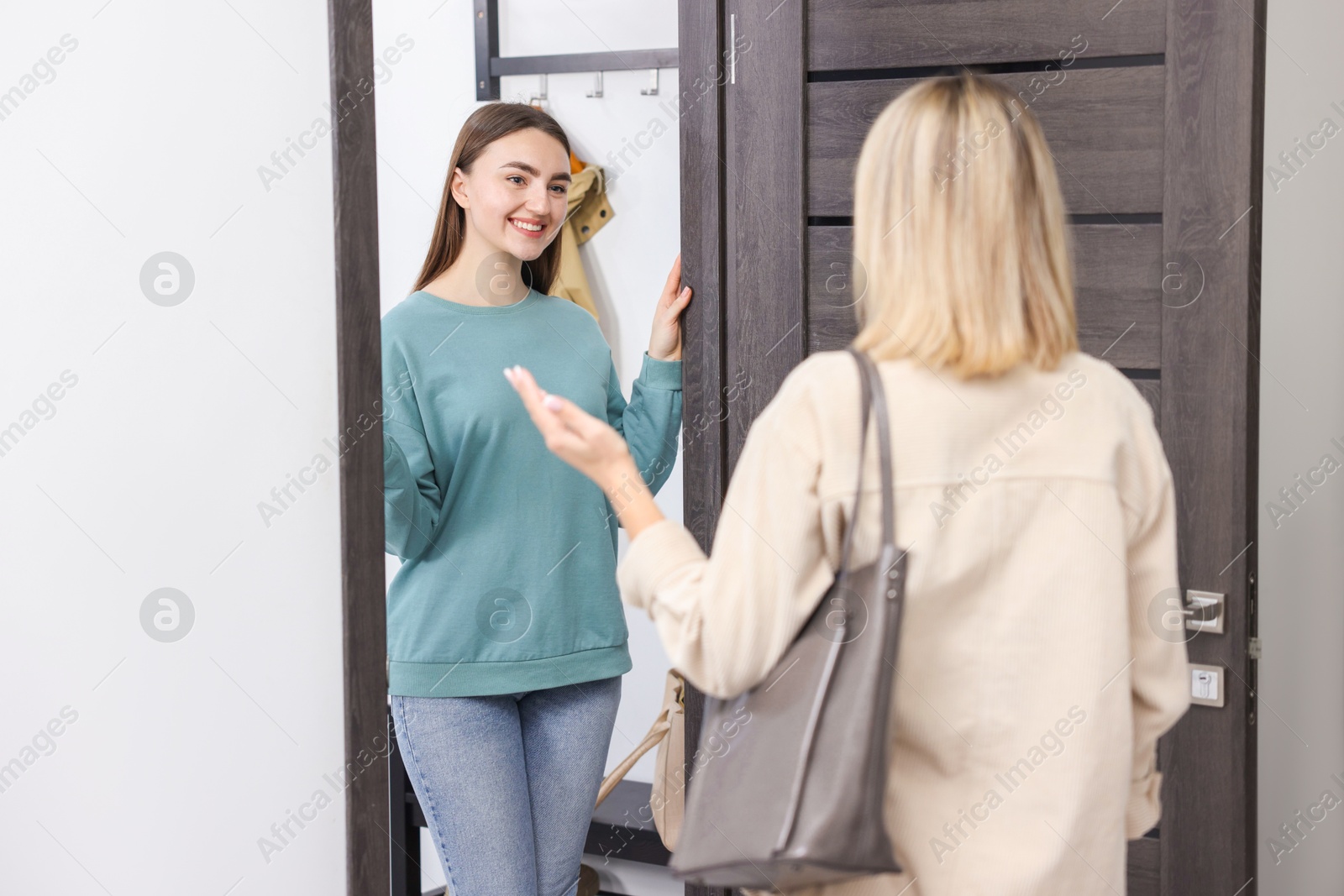 Photo of Happy woman welcoming guest to her apartment