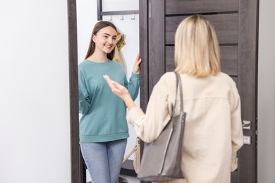 Photo of Happy woman welcoming guest to her apartment