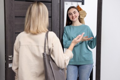 Photo of Happy woman welcoming guest to her apartment